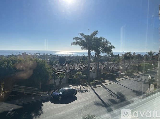 A car is parked on a street with a view of the ocean in the background.