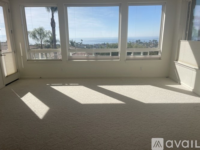 A room with large windows overlooking a coastal area.