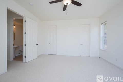 A spacious room with a ceiling fan and three doors.