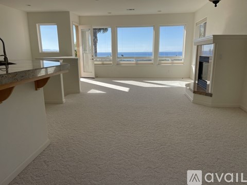 A spacious living room with a view of the ocean through large windows.