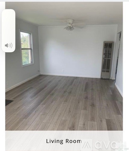 A living room with wooden flooring and a ceiling fan.