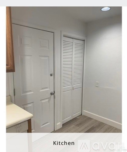 A white kitchen with a white door and a white cabinet.