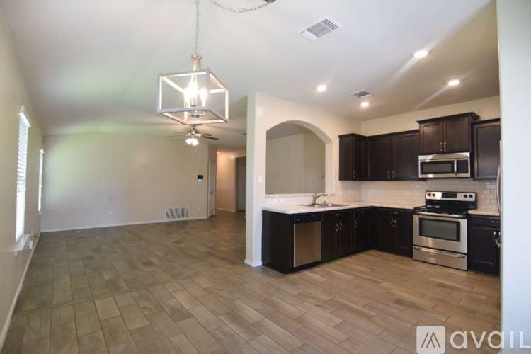 A kitchen with dark brown cabinets and a black countertop.