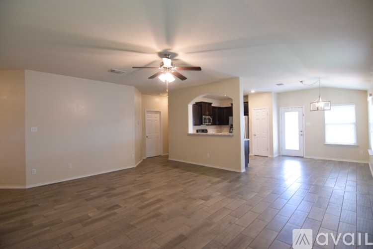 A spacious living room with a ceiling fan and hardwood flooring.