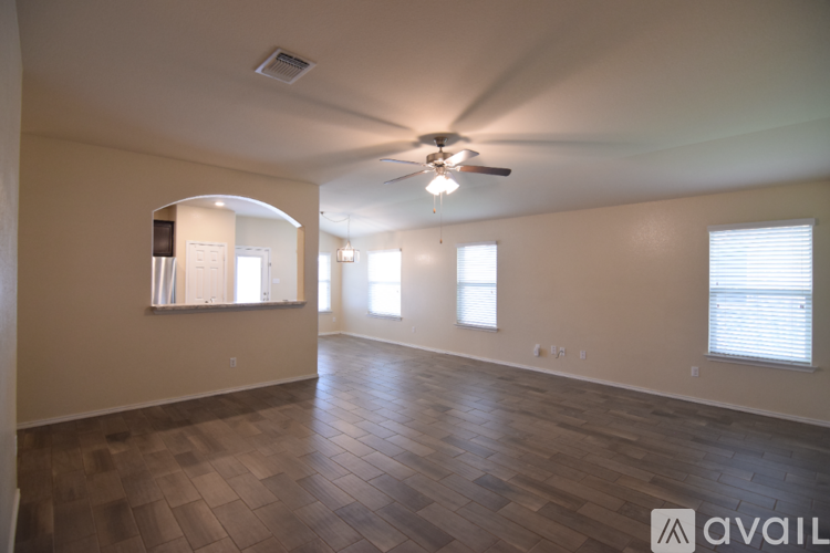 A spacious room with a ceiling fan and hardwood flooring.