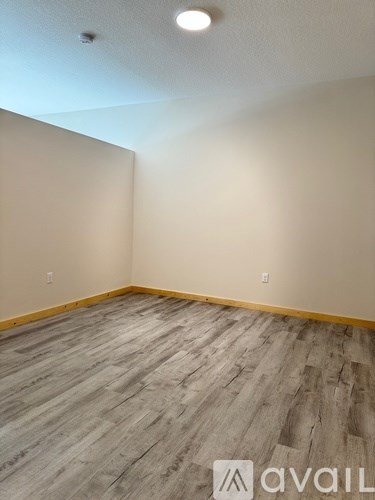 A room with wooden flooring and beige walls.