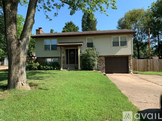 A house with a brown garage door and a tree in front of it.