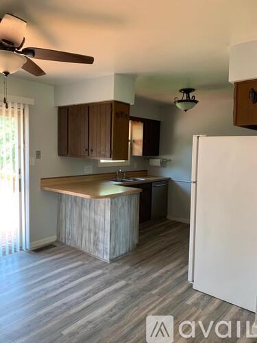 A kitchen with a white refrigerator and wooden cabinets.