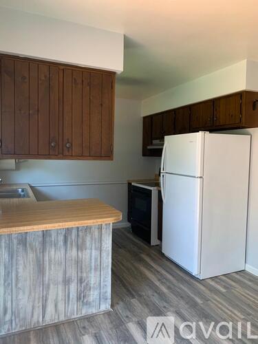 A kitchen with a white refrigerator and wooden cabinets.
