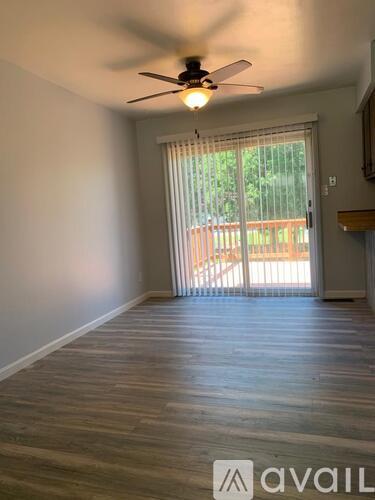 A room with a ceiling fan and sliding glass doors leading to a deck.