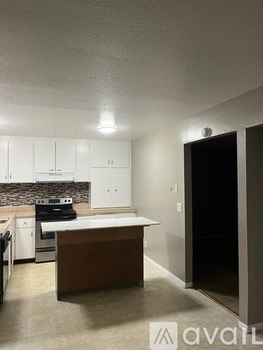 A kitchen with white cabinets and a brown island.