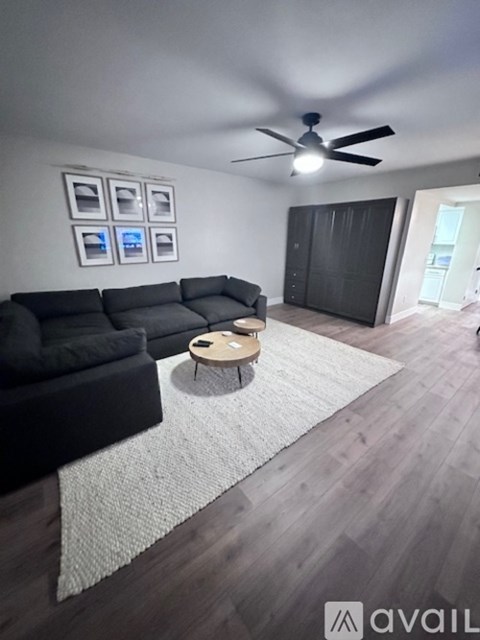 A living room with a black couch and a ceiling fan.