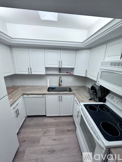 A kitchen with white cabinets and a wooden floor.