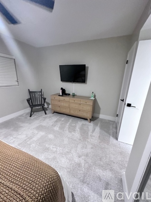 A room with a television, a chair, and a wooden cabinet.