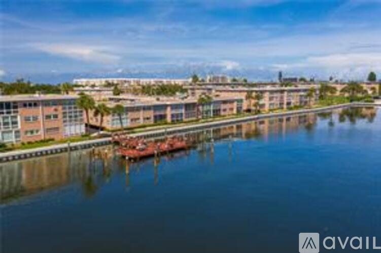 A building complex is situated by a calm body of water with boats docked in front.