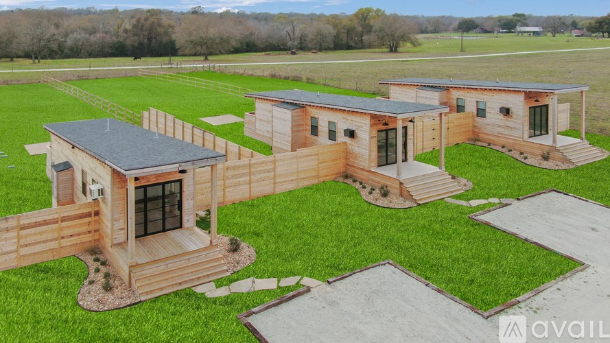 A set of three wooden cabins are surrounded by a grassy area.