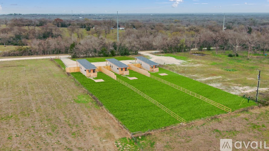 A large open field with a building and a fence in the distance.