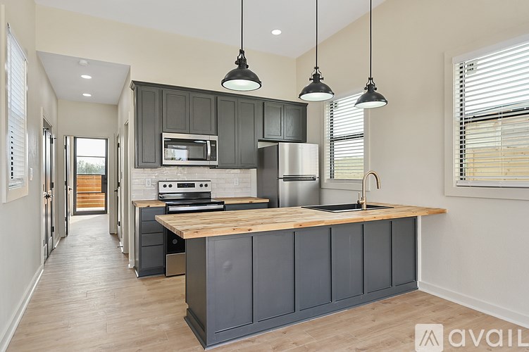 A kitchen with a wooden island and dark grey cabinets.