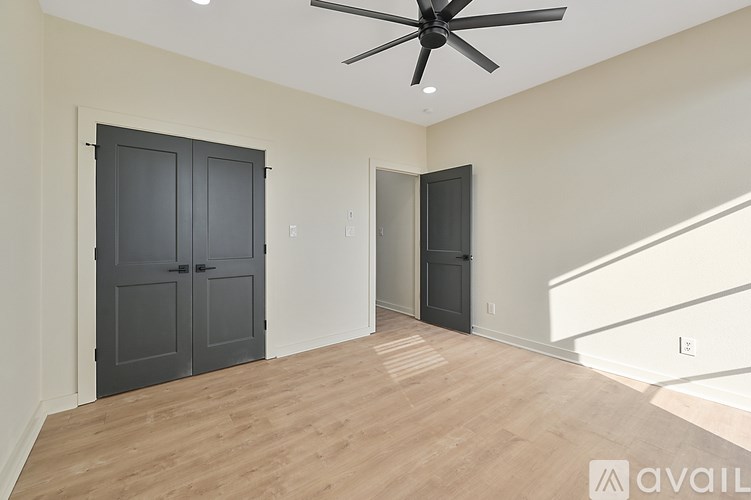 A room with a ceiling fan and two doors.