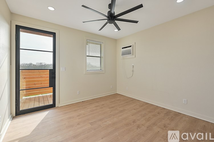 A room with a ceiling fan and a window overlooking a wooden deck.