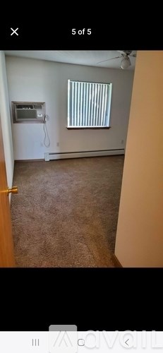 A room with a window covered by blinds and a wall-mounted TV.