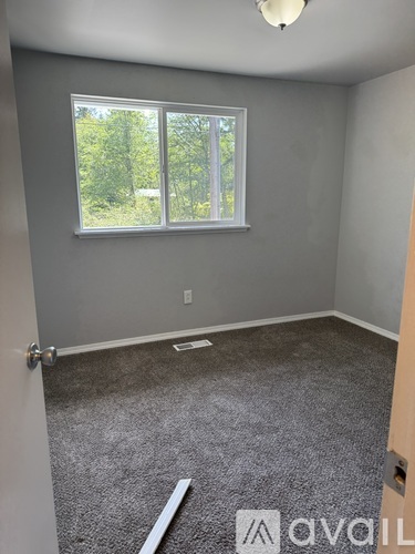 A room with grey walls and a window with a view of trees outside.