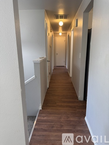A long hallway with wood floors and white walls.