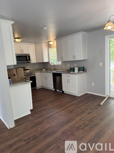 A kitchen with white cabinets and a wooden floor.