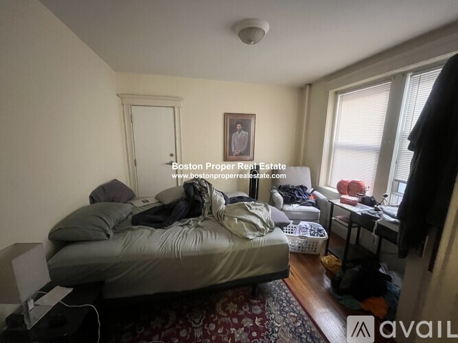 A bedroom with a bed, a desk, and a window.