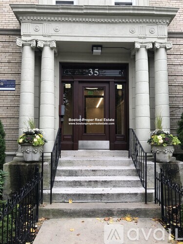 The front of a building with a brown door and a sign that says "Boston Proper Real Estate".