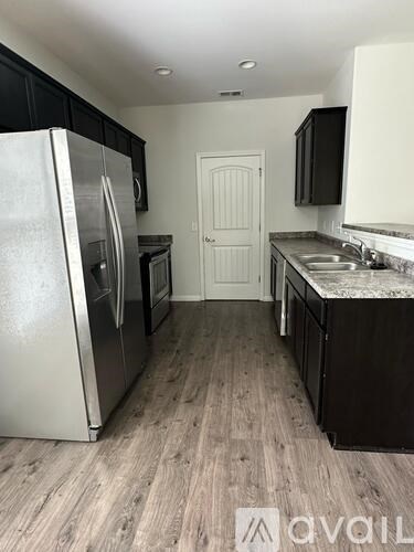 A kitchen with a white refrigerator and black cabinets.