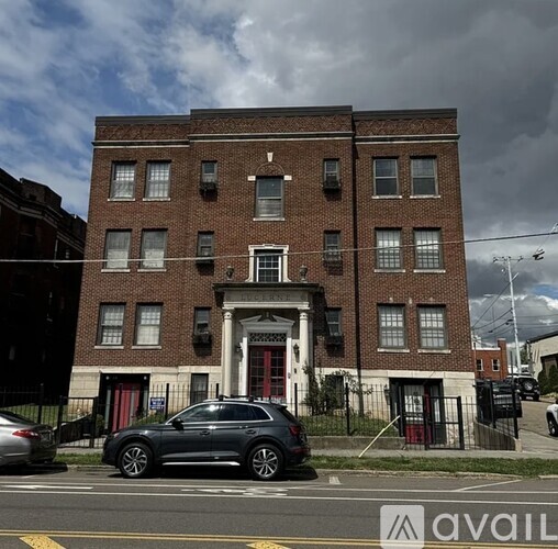 A grey car is parked in front of a red brick building.