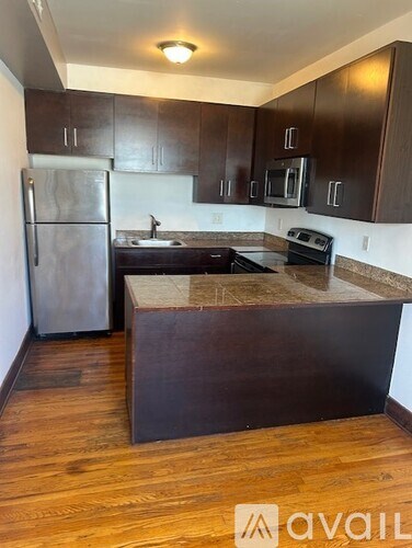 A kitchen with dark wood cabinets and a granite countertop.