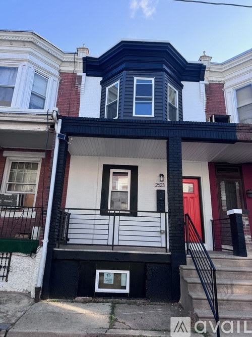 A two-story house with a red door and a balcony.