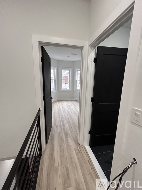A hallway with a black door and a wooden floor.