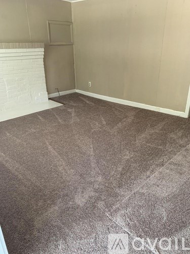 A room with a carpeted floor and a white fireplace.