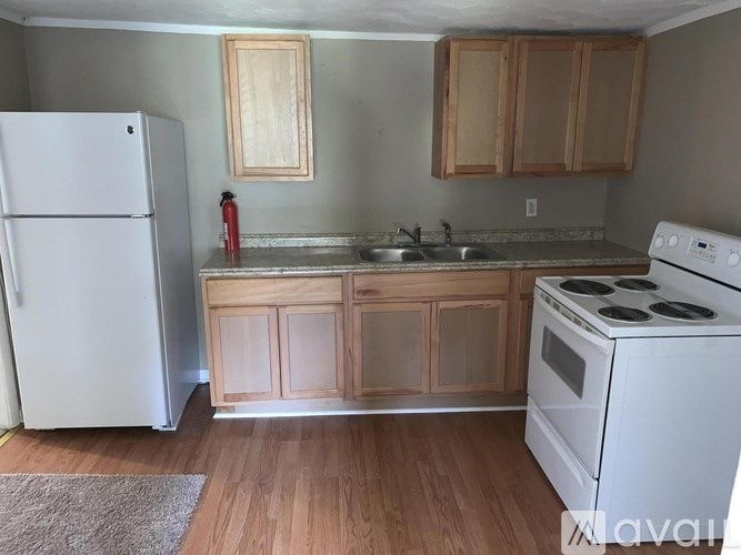 A kitchen with a white refrigerator, a white stove, and wooden cabinets.