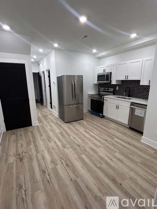 A kitchen with wooden floors and white cabinets.