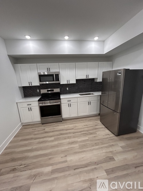 A kitchen with white cabinets and a black fridge.
