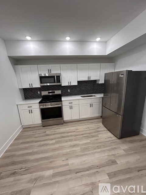 A kitchen with white cabinets and a black fridge.