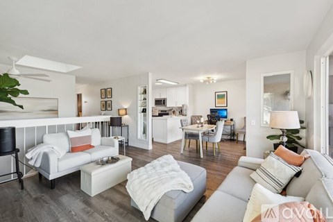 A living room with a white couch and a grey couch with a white blanket on it.
