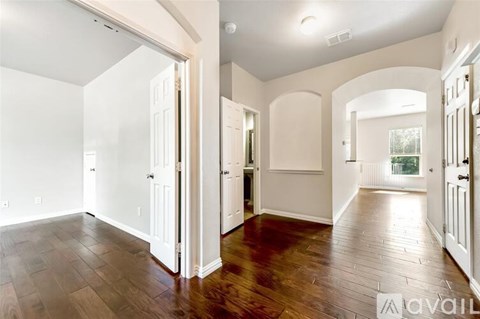 A spacious room with wooden floors and white walls.