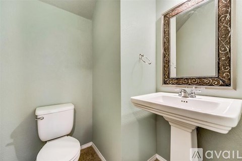 A bathroom with a toilet, sink and mirror.