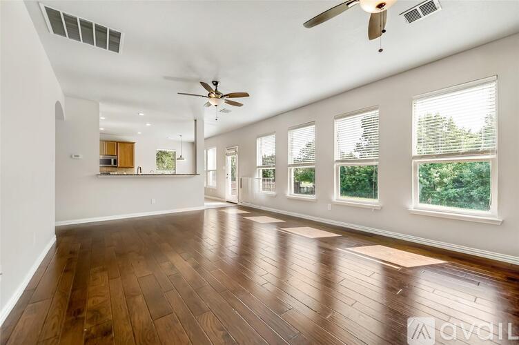 A spacious room with wooden floors and a ceiling fan.