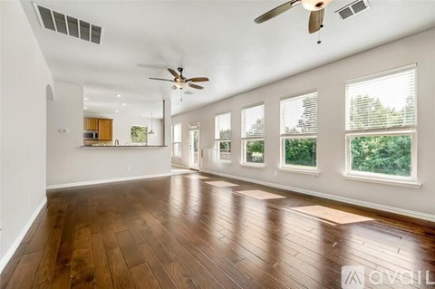 A spacious room with wooden floors and a ceiling fan.