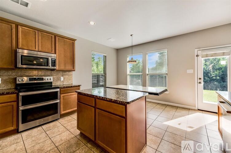A kitchen with wooden cabinets and a granite countertop.