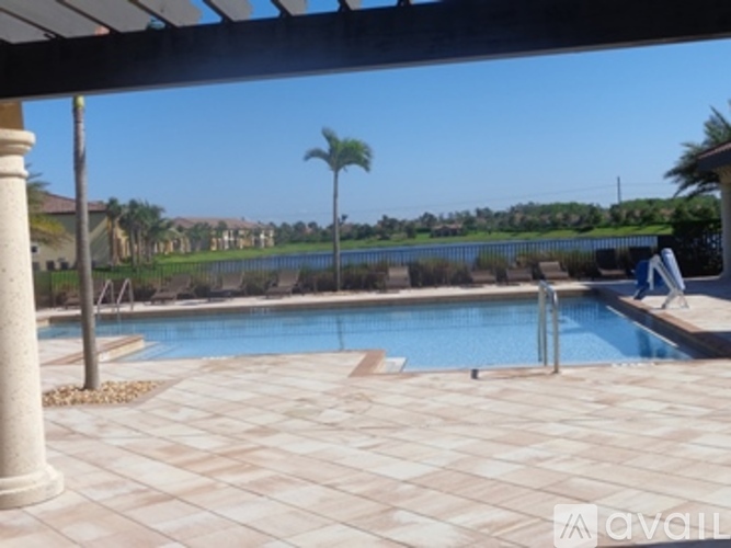 A pool surrounded by a tiled patio and a poolside table.