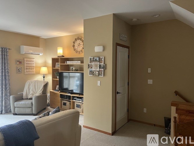 A living room with a television, a chair, and a couch.