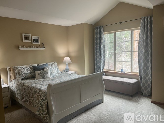 A bedroom with a large bed and a window with curtains.