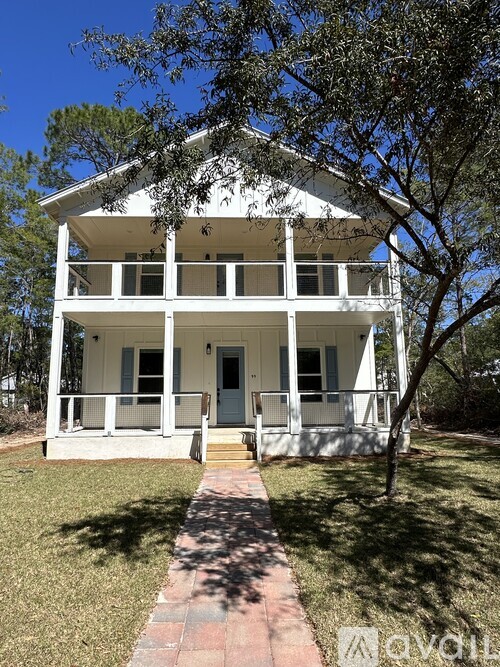 A white two story house with a tree in front.